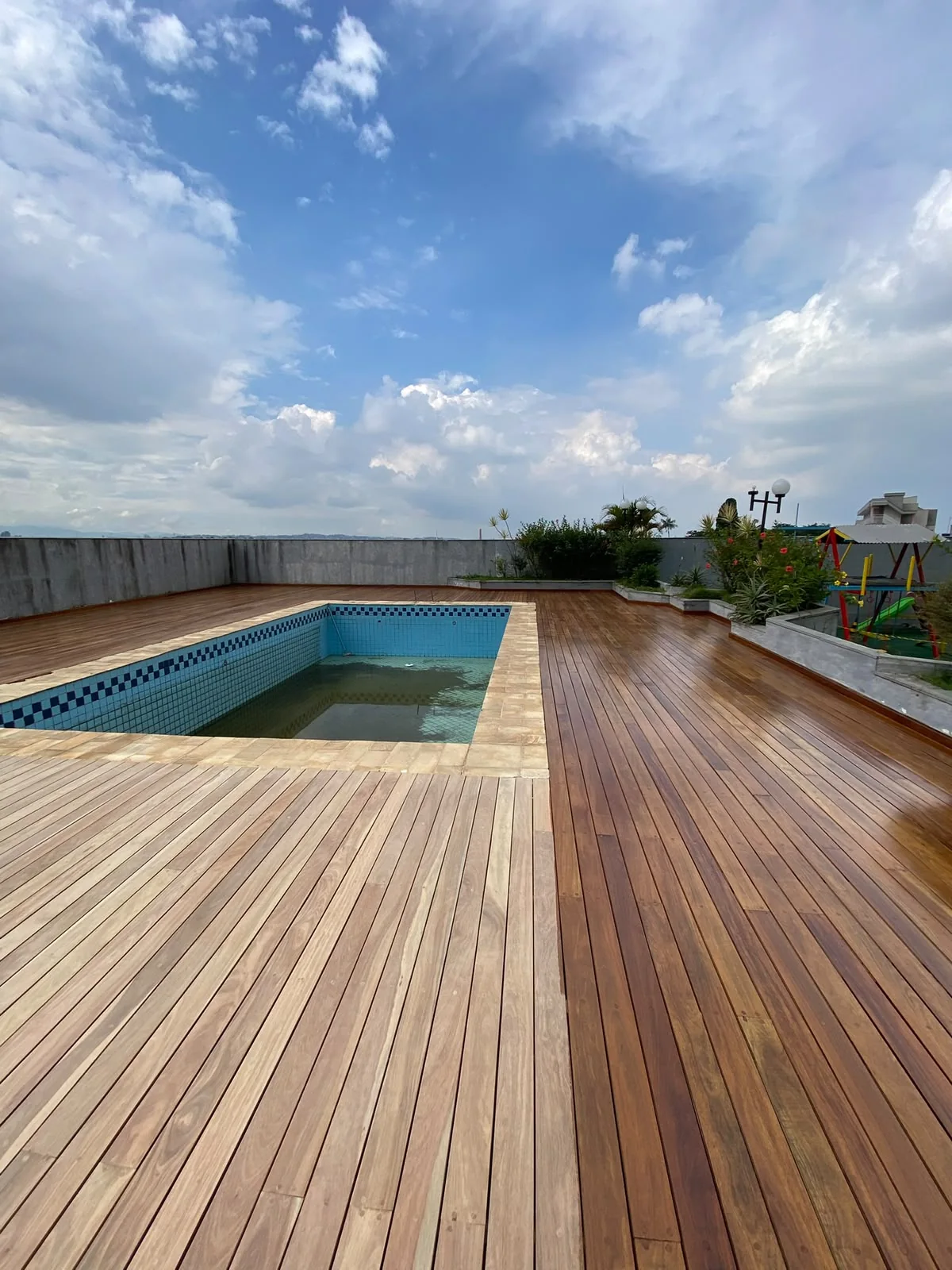 Deck de Cumaru ao redor da piscina, na etapa de aplicação do verniz