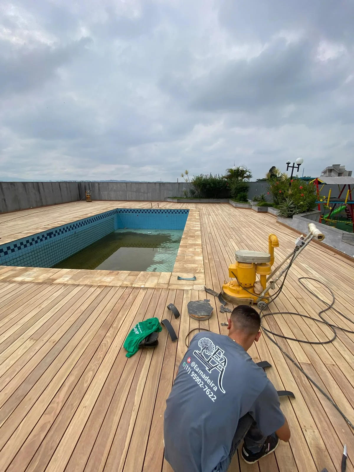 Profissional da EA Madeira trabalhando com equipamento no deck de Cumaru, ao lado da piscina
